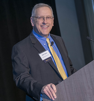 man standing at a podium wearing a suit